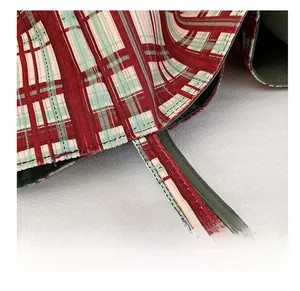 Close-up of tight stitching and fabric texture on a red and green plaid canvas tote bag