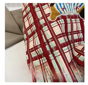 Macro shot of colorful chenille embroidery detail on red and green checkered canvas bag