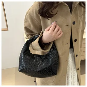 Close-up of black woven hobo handbag featuring intricate leather texture and chic handle