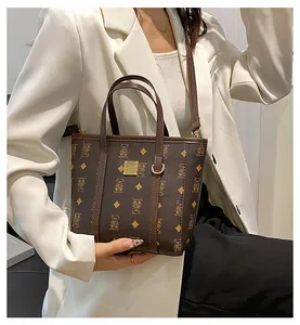 Brown leather tote bag with yellow bear print and golden metal logo plaque detail