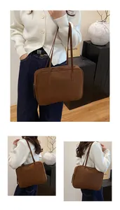 Detail view of brown matte suede shoulder bag featuring top zipper and sturdy straps