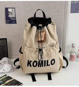 Detail of beige drawstring backpack with black accents and plush toast keychain charm
