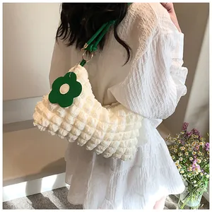 Detailed texture of off-white bubble fabric bag with green strap and flower charm