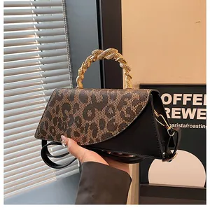 Detail of leopard print flap and elegant gold twisted handle on black crossbody bag