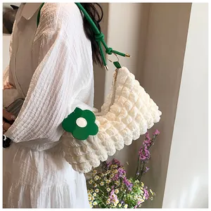 Detail of white popcorn texture fabric with green strap and floral charm on tote bag