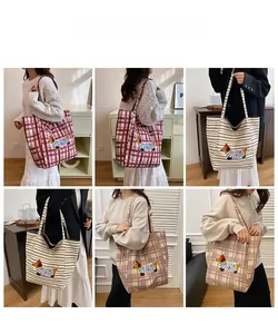 Detail showing checkered canvas tote bags with cartoon dachshund embroidery on model