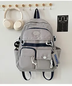 Detailed close-up of light grey campus backpack with navy straps and cute black plush charm