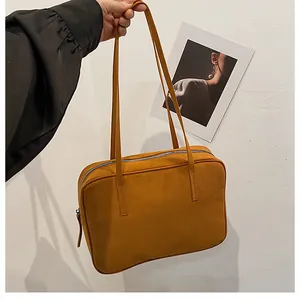 Detail of minimalist orange frosted leather shoulder bag with zipper and hand-stitched strap