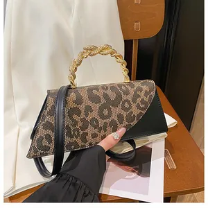 Close-up of leopard print flap and textured gold twist handle on a black leather handbag