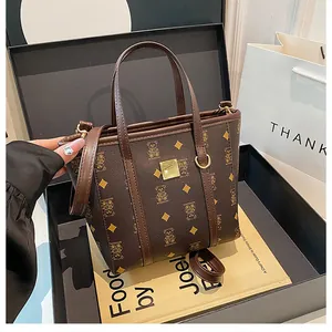 Detail of a brown bucket bag with bear print, shown inside a black gift box packaging