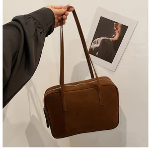Close-up of a deep brown suede shoulder bag with minimalist rectangular design and texture