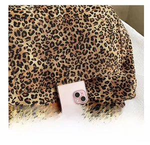 Detailed close-up of leopard canvas tote featuring side pocket with a pink phone