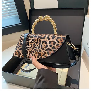 Detail of leopard print crossbody bag with gold twisted handle in a gift box