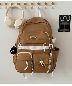Brown canvas college backpack with multi-pockets and black plush ball hanging detail