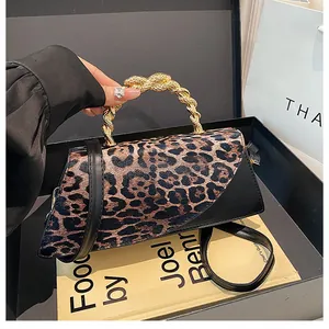 Close-up of leopard print handbag featuring a gold spiral metal handle and black strap