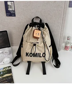Detail of khaki nylon drawstring backpack with bear charm and Komilo lettering