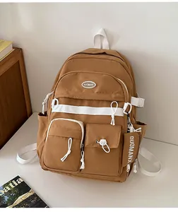Detail of khaki campus backpack featuring functional pockets and white ribbon zip pulls