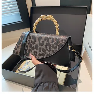 Detail of leopard print fabric handbag featuring a luxury gold snake-shaped metal handle