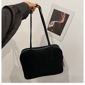 Close-up of minimalist black matte tote bag with silver zipper held by a hand