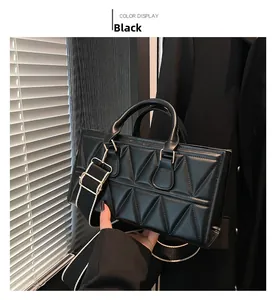Detail of black rectangular handbag with triangle quilted texture and wide canvas strap