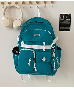 Detailed view of lake blue multi-pocket backpack with plush charm and mini pouch