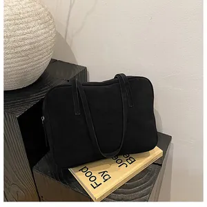 Detailed side view of black matte suede tote bag with zipper and dual shoulder straps