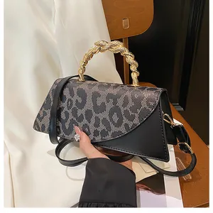 Detail of leopard print crossbody bag featuring a unique braided gold metal handle