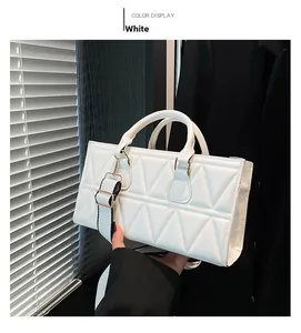 Detail of white quilted handbag with wide shoulder strap and textured triangle pattern