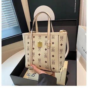 Detail of cream white bucket bag with bear patterns and gold hardware in a gift box