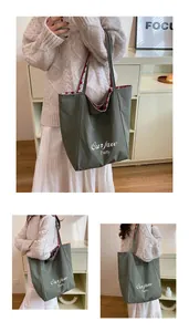 Detail of green canvas tote bag featuring red and white plaid lining and white slogan print