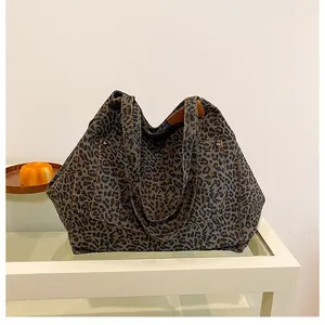 Detail of leopard print tote bag with thick canvas texture and metal rivet reinforcement