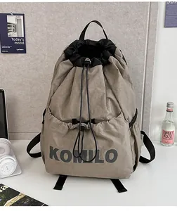 Detail view of khaki drawstring backpack with black accents and KOMILO branding logo
