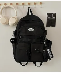 Detail of a black multi-pocket nylon backpack featuring a plush ball charm and card hook