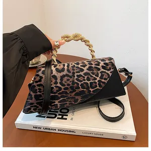 Detail view of leopard print texture and gold spiral handle on a mini crossbody bag