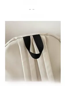 Detail view of the durable black woven handle and cream-colored fabric of the backpack