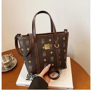 Detail of dark brown tote bag with bear pattern on white book prop in warm setting
