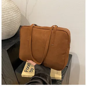 Detailed close-up of brown suede shoulder bag texture and dual slender carry straps