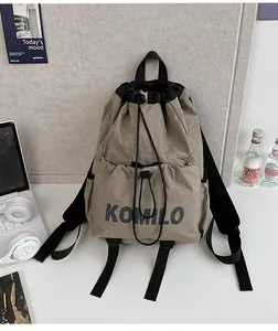 Detail of khaki drawstring backpack with front pocket and KOMILO logo on nylon fabric
