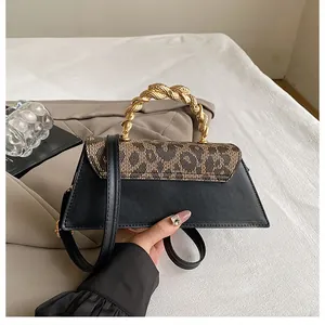 Detail of leopard print crossbody bag with a chunky gold woven metal handle