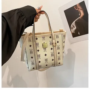 Detail of cream tote bag with bear print, diamond pattern, and gold metal square buckle