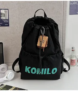 Detail of black canvas drawstring backpack with mint green KONILO text and toast plush charm