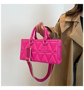 Detail of fuchsia quilted handbag with geometric patterns and broad canvas shoulder strap