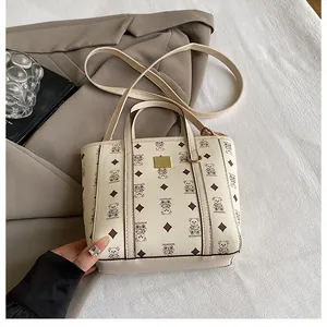 Detail of cream bucket bag with bear print on grey blazer and white fabric