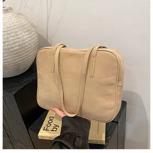 Detail of light brown matte leather tote bag with slim handles and silver top zipper closure