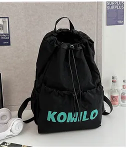 Close-up of lightweight black nylon drawstring backpack with teal KOMILO lettering