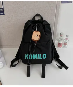 Close-up of black nylon drawstring bag with KOMILO print and toast plush pendant