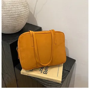 Detailed view of ginger yellow frosted suede tote bag with slim handles on a display stand