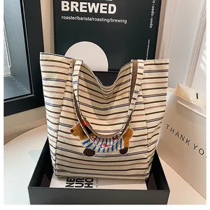 Detail view of a striped corduroy tote bag with cute dachshund embroidery in a gift box
