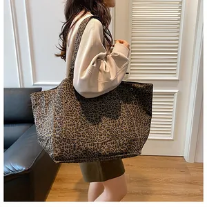 Detailed view of leopard print tote bag with wide shoulder strap and metal rivets