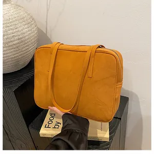 Detailed top view of mustard yellow suede shoulder bag with slim straps and zipper closure